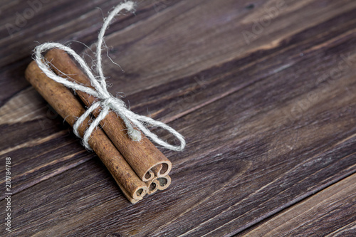 three cinnamon stick tied with rope, at the brown wooden table