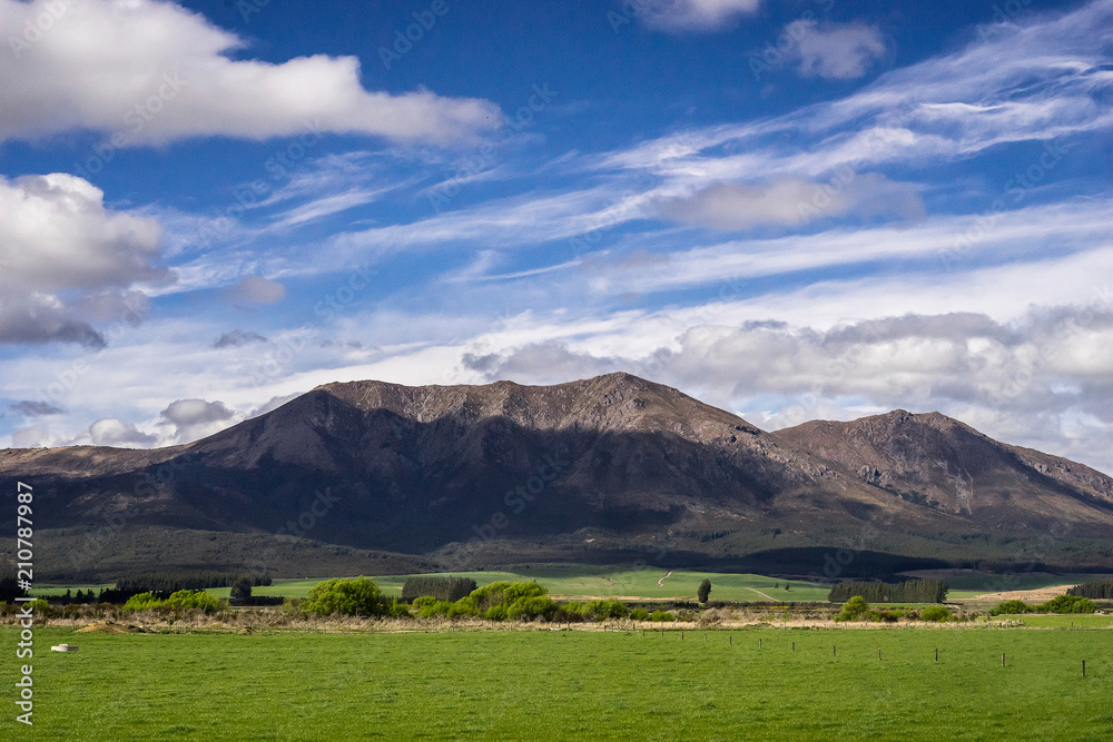 Naklejka premium New Zealand scenery mountains and green grass field with cloudy blue sky over the mountain