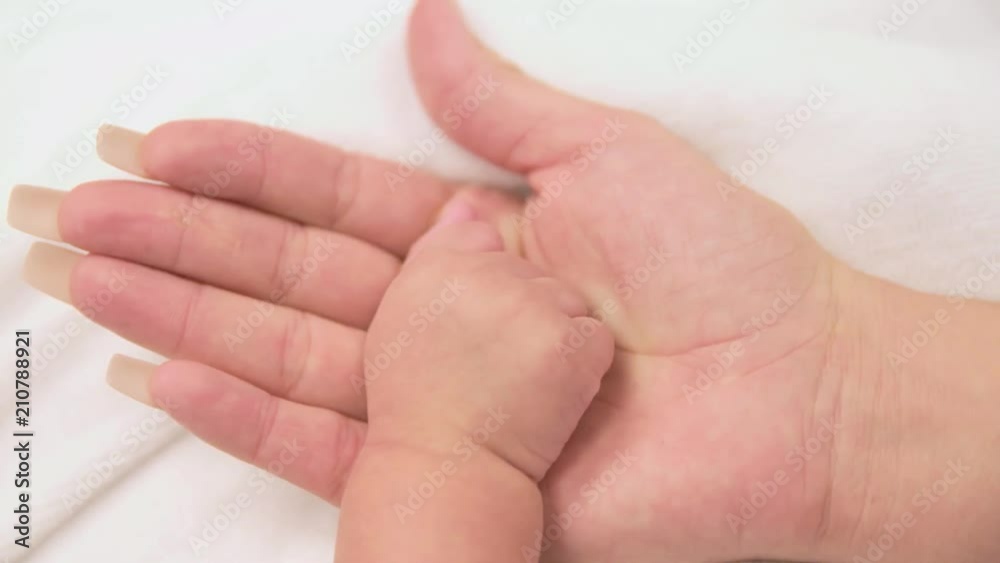 Mother's hand opening as his baby's hand is revealed inside of her's. Mother's hand opening as his baby's hand is revealed inside of her's.