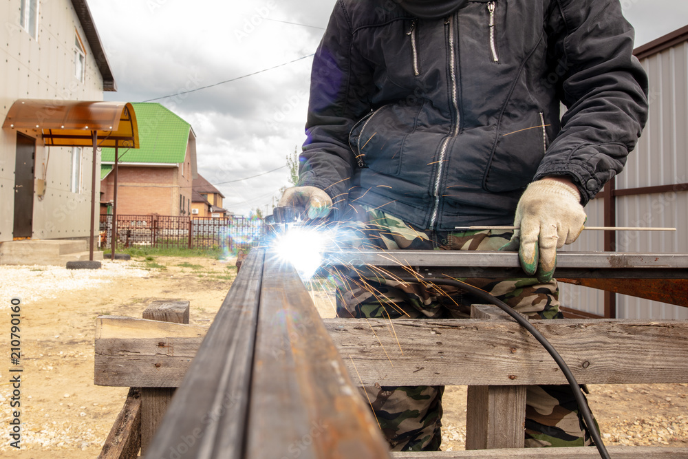 Welder welds metal at the construction site Welder welds metal at the construction site