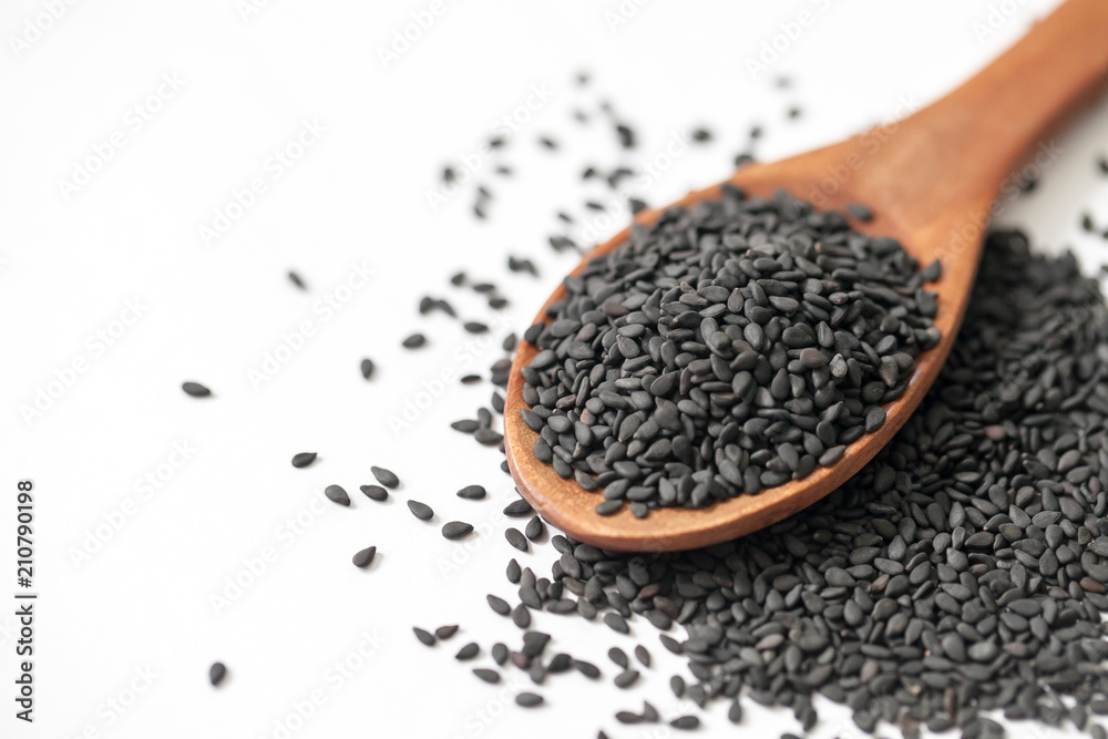 black sesame seeds in wooden spoon on white background black sesame seeds in wooden spoon on white background