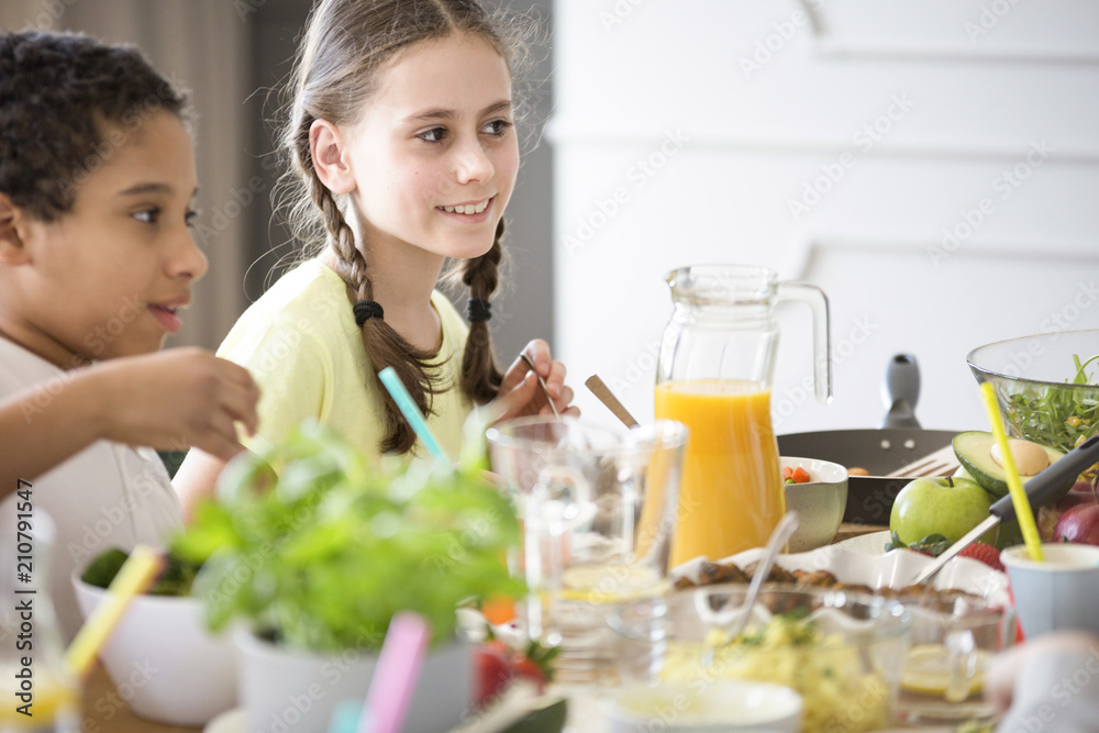 A girl and a boy by a table full of healthy homemade food and freshly squeezed orange juice celebrating Children's Day at a friend's house A girl and a boy by a table full of healthy homemade food and freshly squeezed orange juice celebrating Children's Day at a friend's house