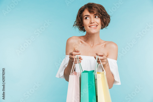 Portrait of a smiling pensive woman holding shopping bags photo