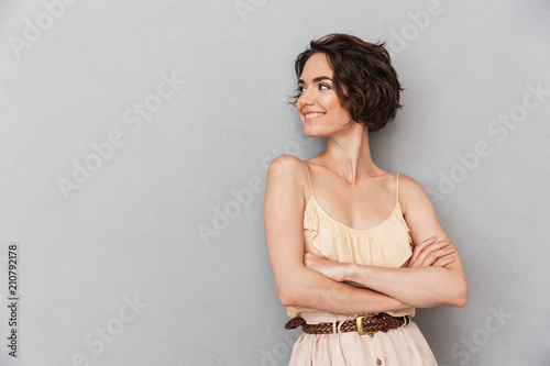 Portrait of a smiling young woman standing with arms folded photo