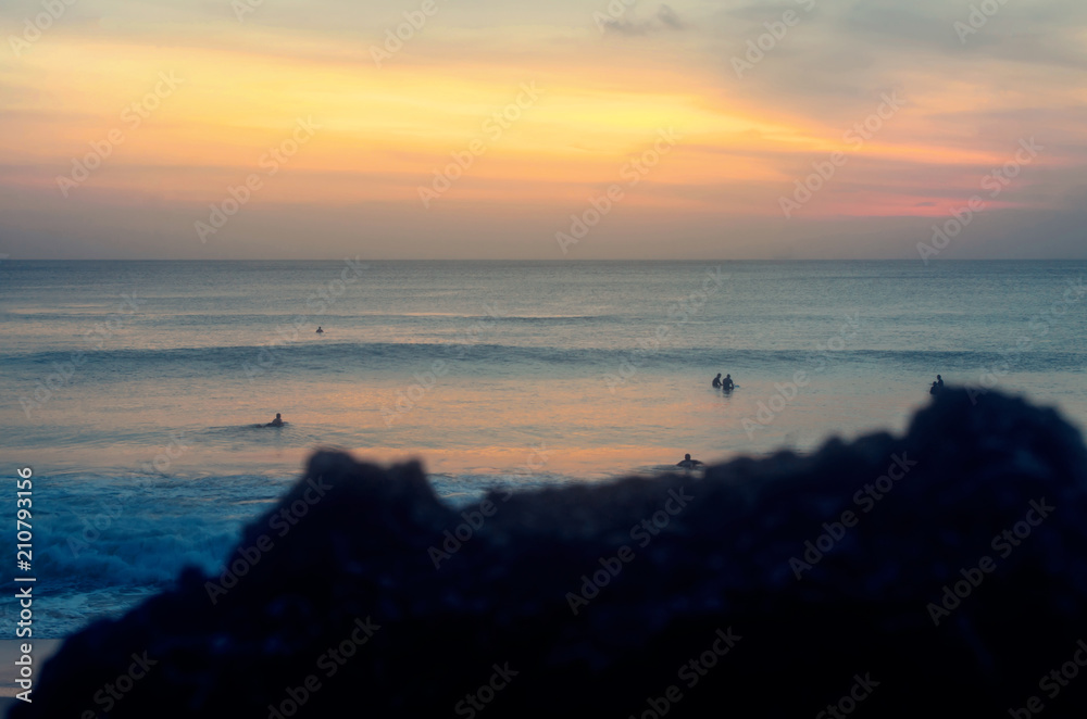 Beautiul sunset on a tropical island. Surfers enjoying challenges of surfing.