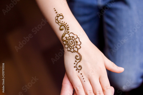 hand of small girl being decorated with henna mehendi Tattoo. Close-up, overhead view - beauty concept