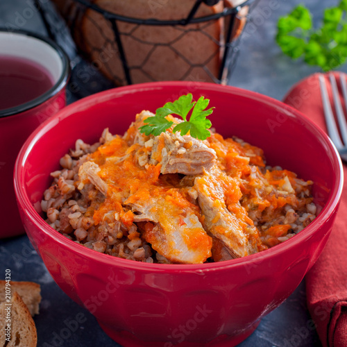 Buckwheat porridge with meat and carrots in a red bowl, square photo