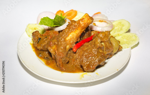 Popular Indian meal of spicy mutton meat gravy popularly known as mutton kosha with chili and sliced vegetables.