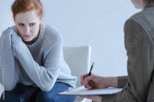 Sad young woman with eating disorders during meeting with psychotherapist