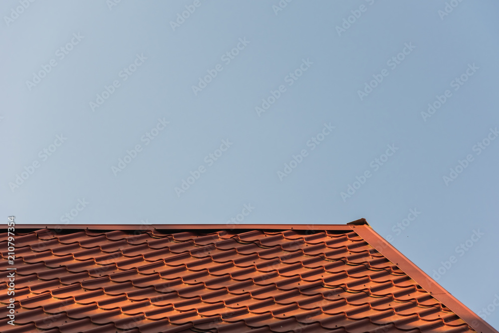 the top of the roof of an iron tile against the background of a blue sky the top of the roof of an iron tile against the background of a blue sky