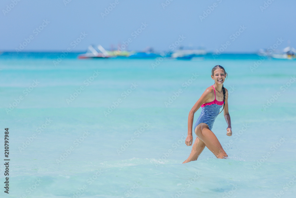 Girl in swimsuit runing and having fun on tropical beach