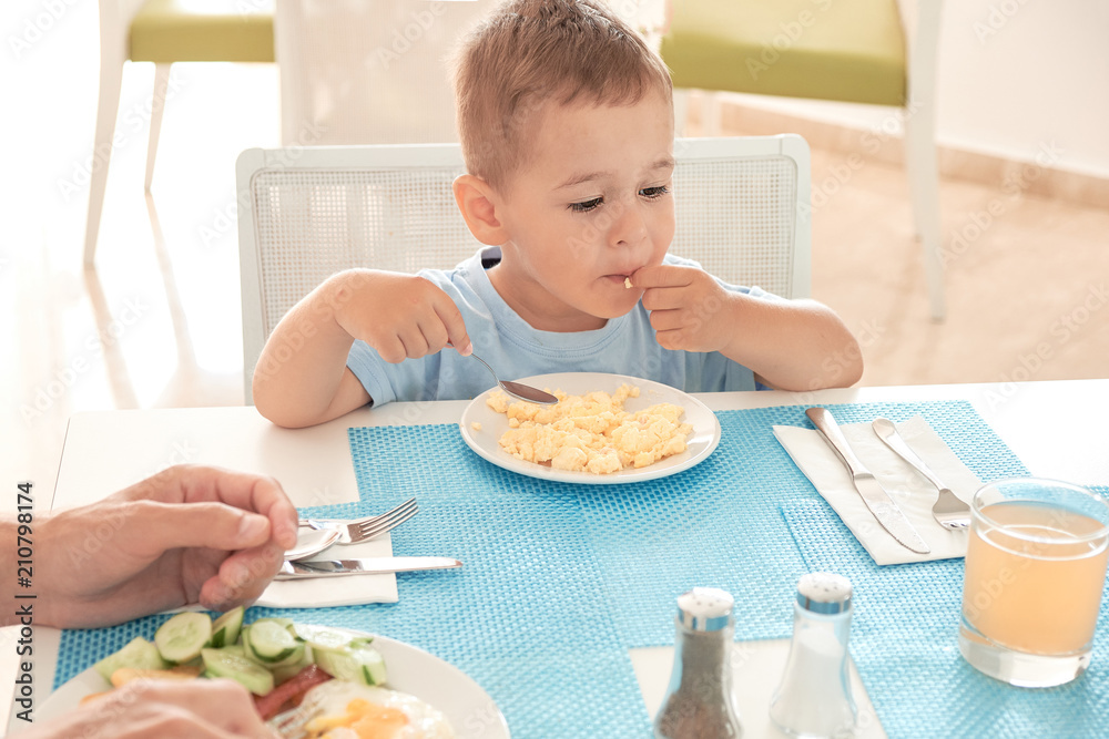 funny boy has Breakfast eggs alone holding a spoon. funny boy has Breakfast eggs alone holding a spoon.