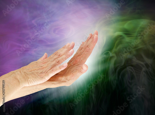 Controlling the negative energy field of an energy vampire - female hands appearing to push white light into dark green depicting energy control 
