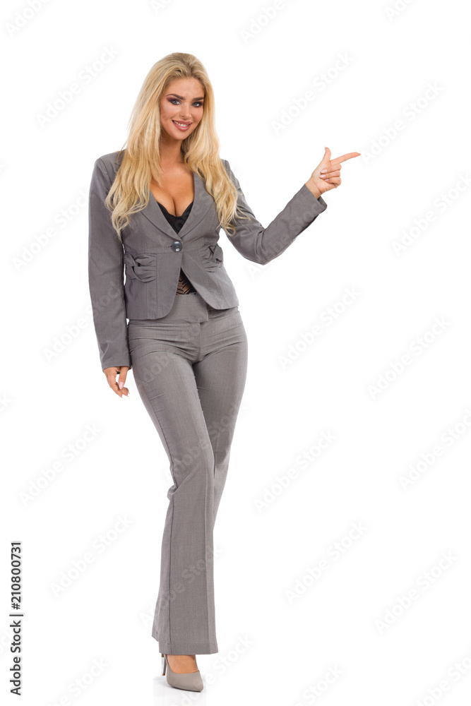 Smiling Woman In Gray Suit Is Standing And Pointing Smiling Woman In Gray Suit Is Standing And Pointing