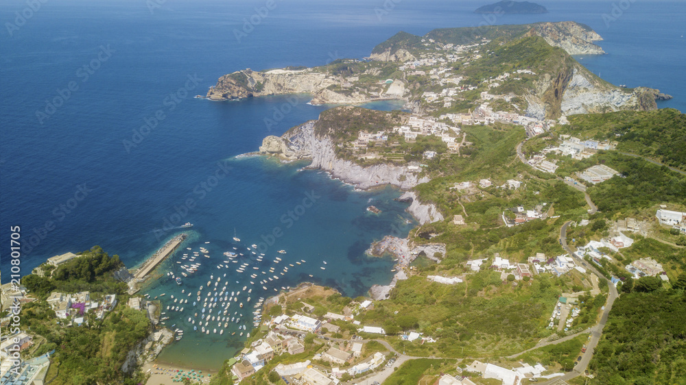 Aerial view of the beach and the small harbor of Cala Feola on the island of Ponza, in Italy. There are many boats and motorboats of tourists anchored in the bay and sheltered in the mountains.