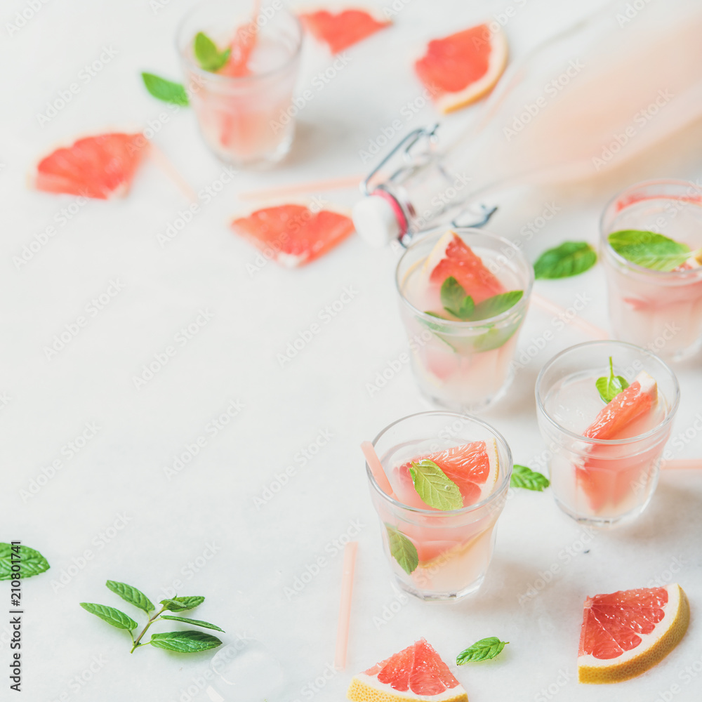 Flat-lay of cold refreshing summer alcohol cocktail with fresh grapefruit, mint and ice in glasses over white marble background, copy space, square crop Flat-lay of cold refreshing summer alcohol cocktail with fresh grapefruit, mint and ice in glasses over white marble background, copy space, square crop