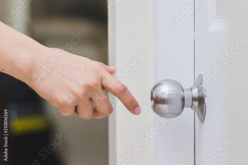 close up of woman’s hand reaching to door knob, opening the door photo