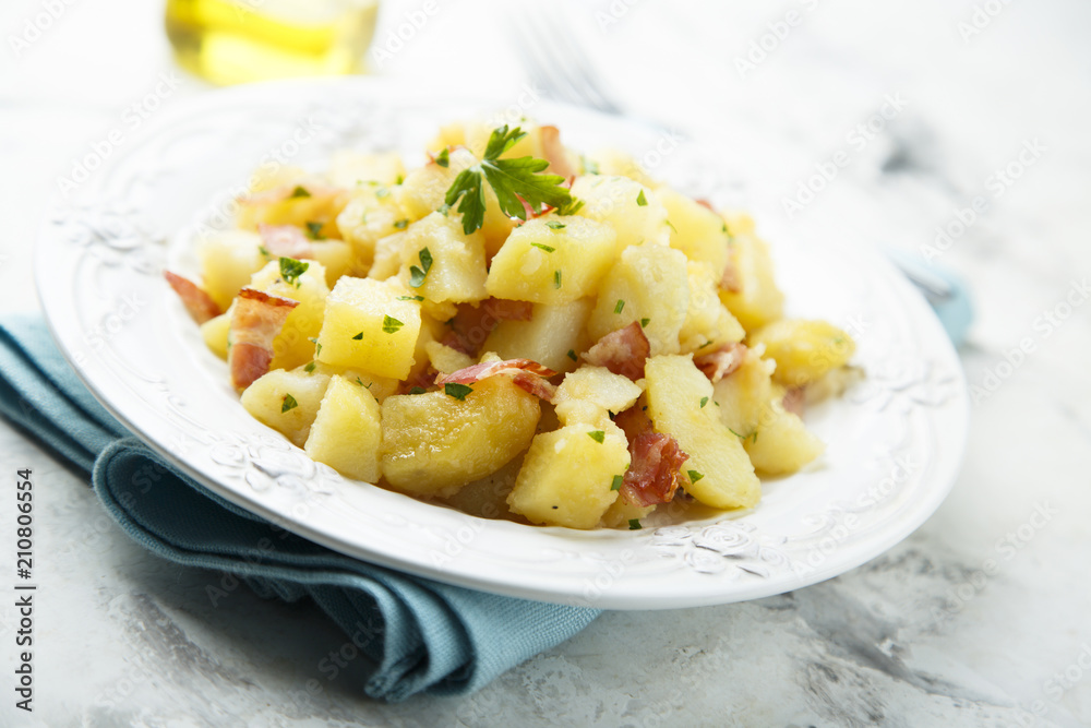 Homemade warm potato salad with onion and fried bacon