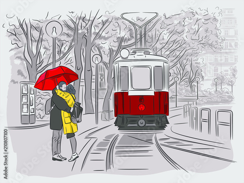 The guy and the girl are waiting for the tram under the umbrella. Cityscapes of Vienna