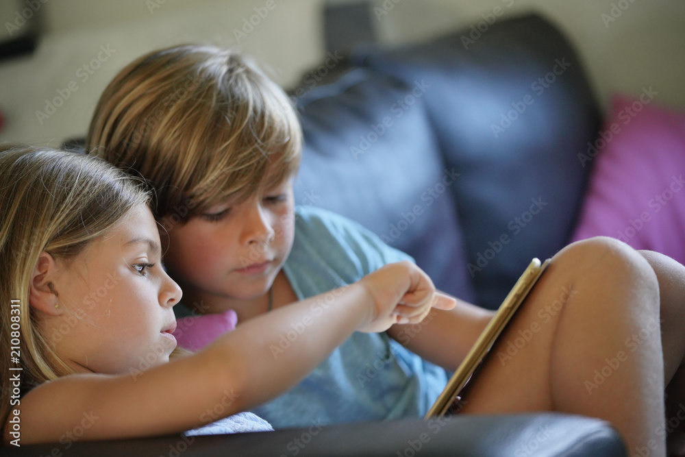 Kids playing with digital tablet, sitting on couch Kids playing with digital tablet, sitting on couch