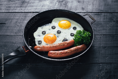 scrambled egg with sausages in the pan and tomatoe juice on black background. Copy space