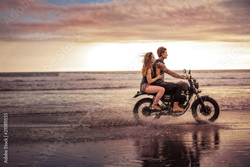 side view of couple riding motorcycle on ocean beach