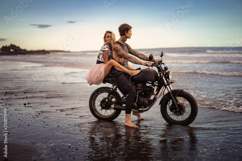 side view of couple hugging on motorcycle on ocean beach