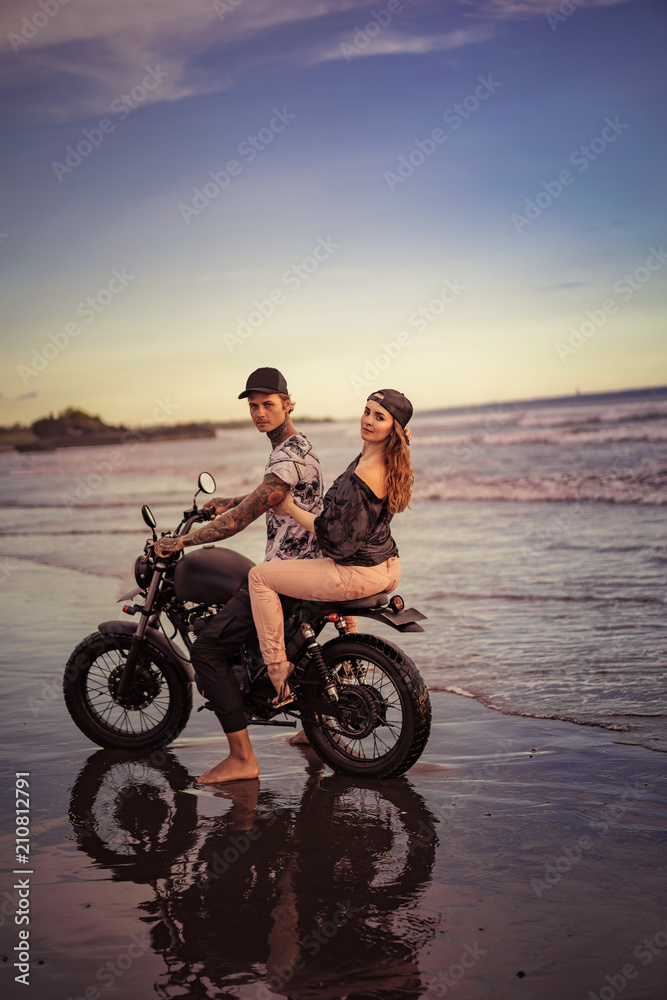 Fototapeta premium side view of couple riding motorcycle on seashore