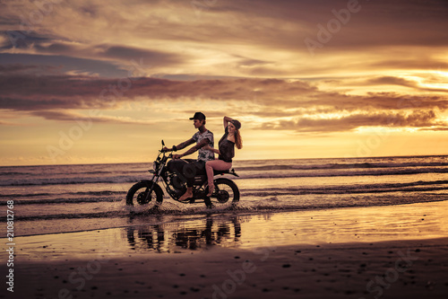 affectionate couple riding motorcycle on ocean beach