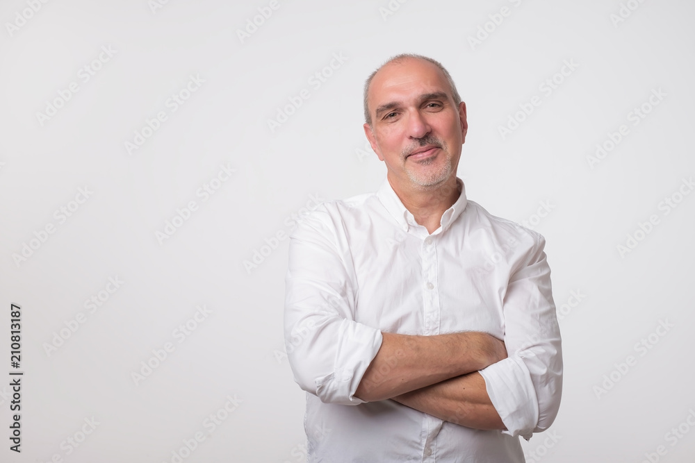 Confident senior man in white t-shirt crossing hands on chest and looking at camera Confident senior man in white t-shirt crossing hands on chest and looking at camera