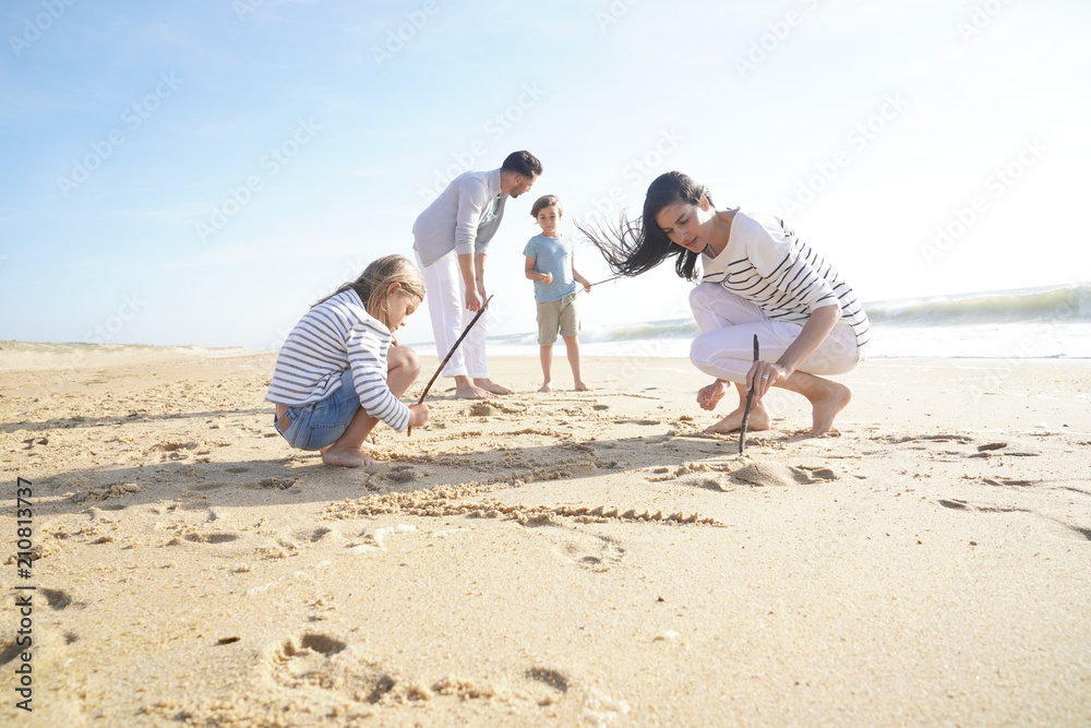 Family having fun writing messages on sandy beach Family having fun writing messages on sandy beach