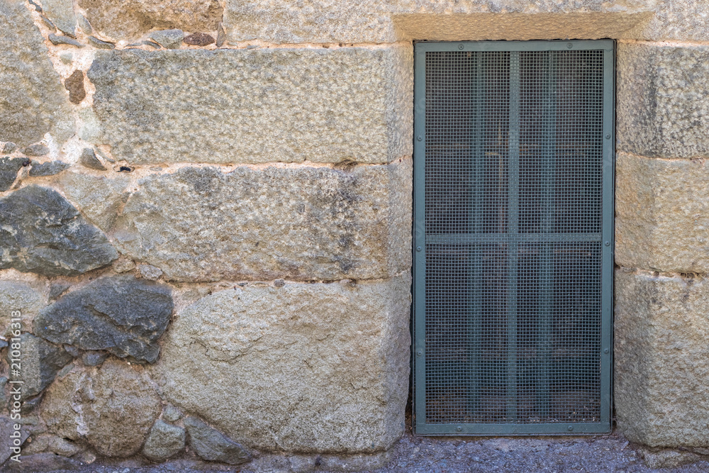 A passage with a small metal grate in a stone wall, background A passage with a small metal grate in a stone wall, background