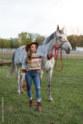 Beautiful young woman with white horse outdoors. Love animal. Cowgirl in jeans. Happy girl