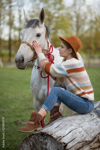 Beautiful girl taking care of her horse. Focus on girl. Warm image tone. Soft focus