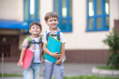 Cute little school students briskly talk on the schoolyard. Children have a good mood. Warm spring morning. photo