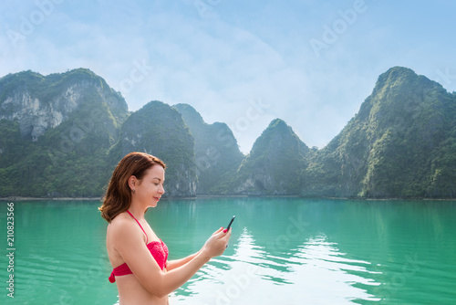 Woman traveling by boat among the islands and using mobile
