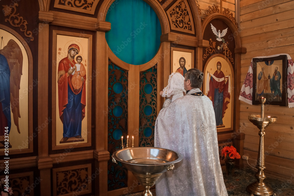 the priest carries the child on his hands to the altar, baptism in the Orthodox Church