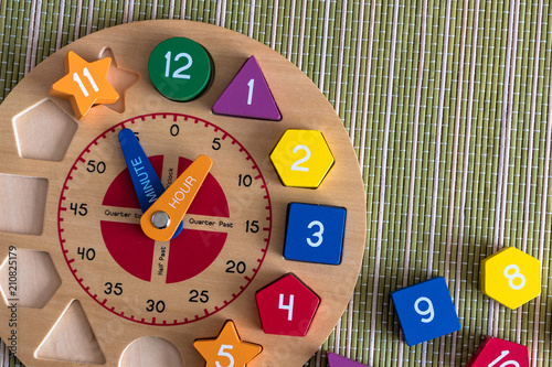 Wooden toy clock on a green, bamboo mat