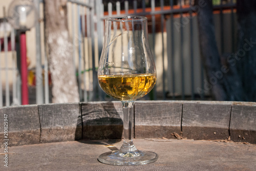 White semi-sweet wine in a glass, on old vintage wooden barrel