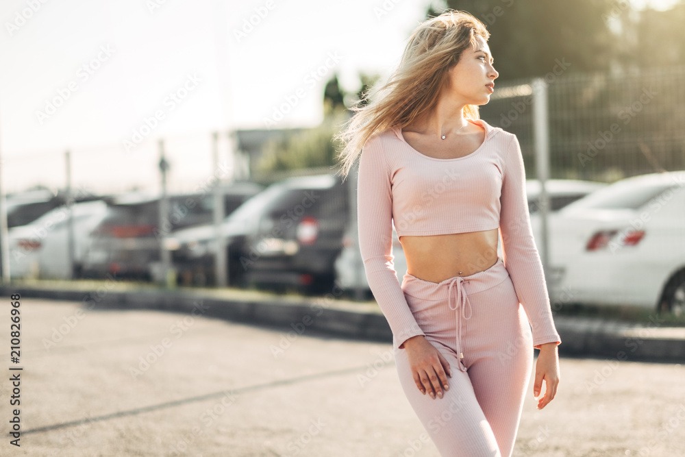 Portrait of Young and Beautiful Woman in Casual Clothes in the Street. Dressed in Pink Shirt and Pants. Spring, Summer Concept. Relax Time. Girl with Sunglasses. Enjoy City Sunset.