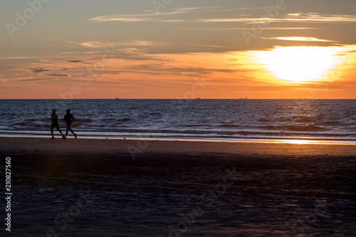 Couple silhouette running during sunset at the beach