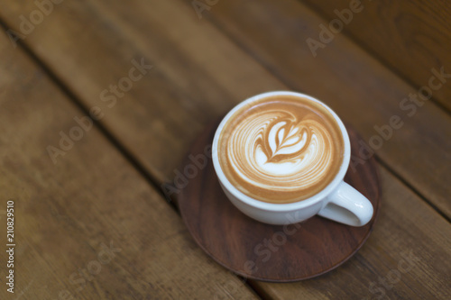 Beautiful cup of cappuccino with trendy latte art on the wooden background