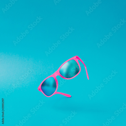 Pink sunglasses on pastel blue background. Minimal summer concept. Semi flat lay.