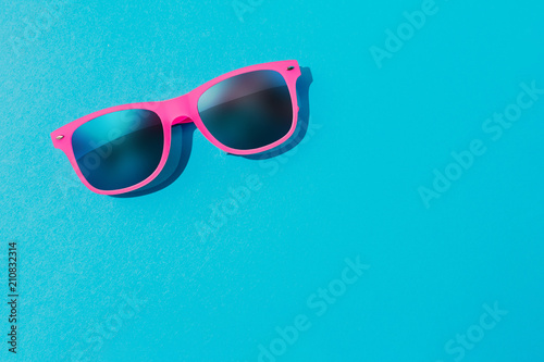 Pink sunglasses on pastel blue background. Minimal summer concept. Flat lay.