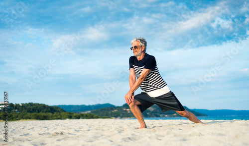 Senior man doing stretching exercises on the beach