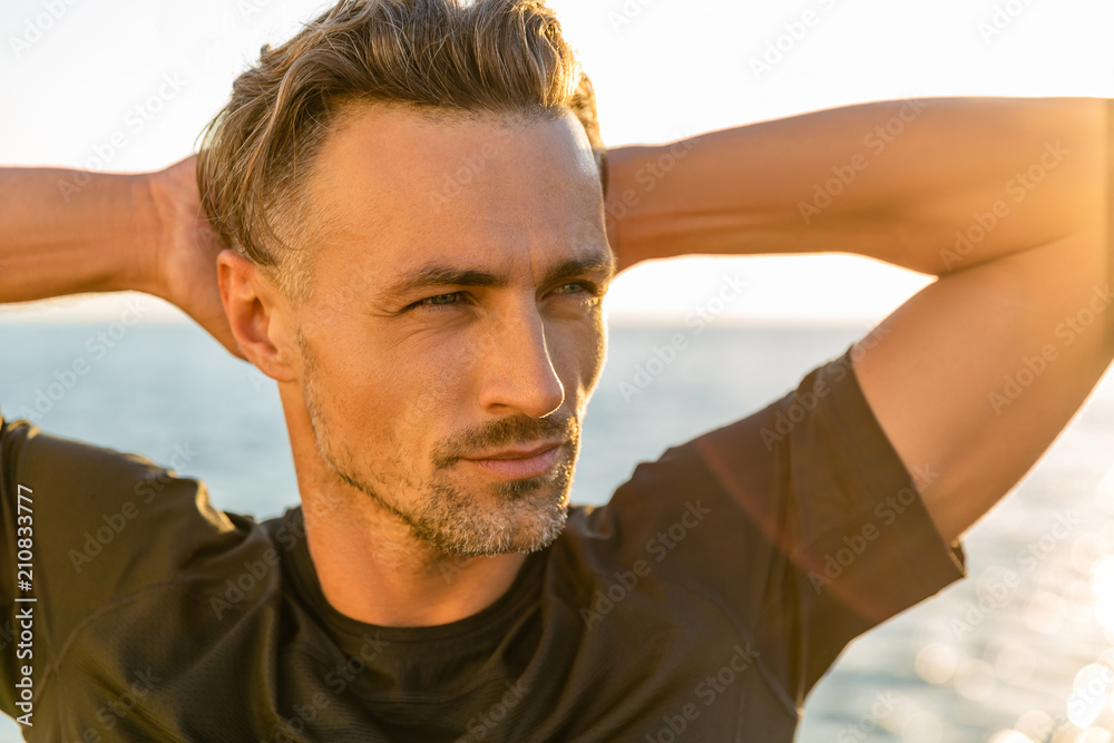 Obraz premium close-up portrait of handsome adult man on seashore in front of sunrise