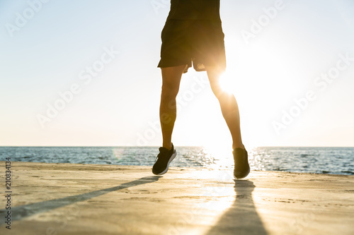 handsome adult sportsman jumping on seashore