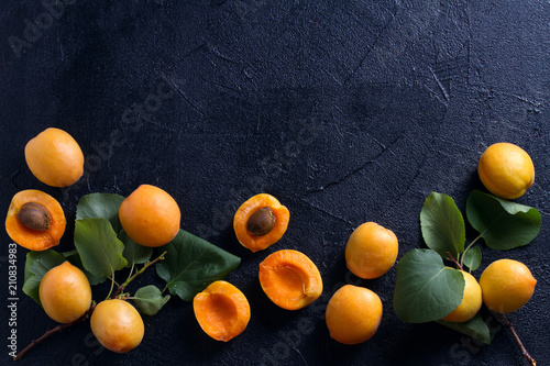 Delicious ripe apricots  on black background, close-up. Fruit banner. Selection of healthy vegetarian food, detox or diet concept, space for text. View from above, top studio shot