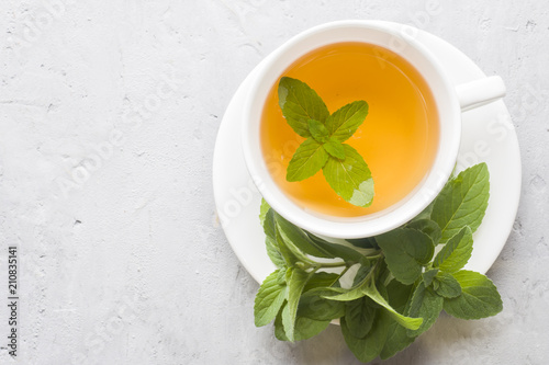 Cup of tea with fresh mint leaves on grey concrete background. Copy space