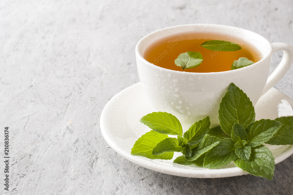 Cup of tea with fresh mint leaves on grey concrete background Cup of tea with fresh mint leaves on grey concrete background
